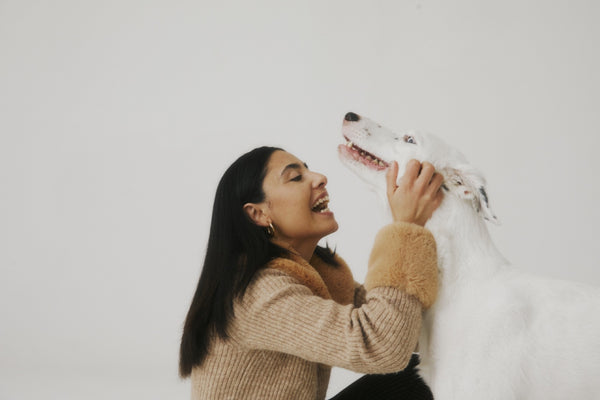 Woman laughing with her whippet in a bright studio