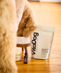VitaDog Nutrition product on a wooden floor with a fluffy dog in the foreground