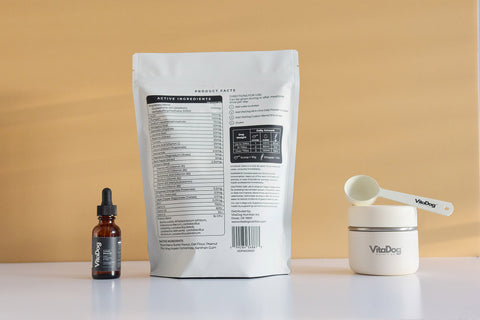 VitaDog Nutrition set including a bottle, pouch, scooper and shaker on a beige background